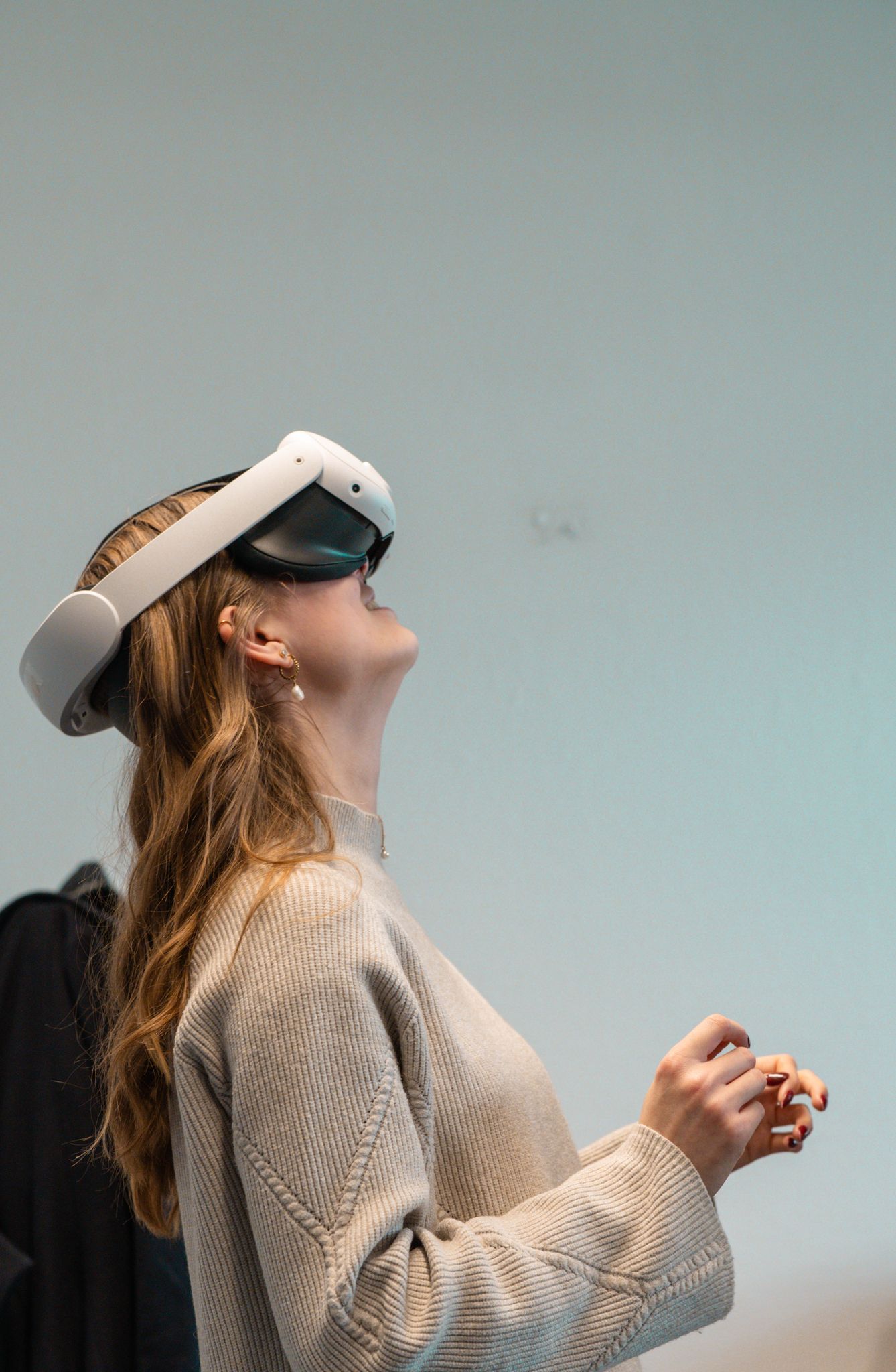 A woman wearing a virtual reality headset, immersed in a digital experience indoors.