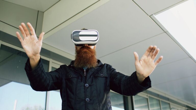 Bearded man wearing VR headset interacts outside modern building. Experiencing virtual reality.